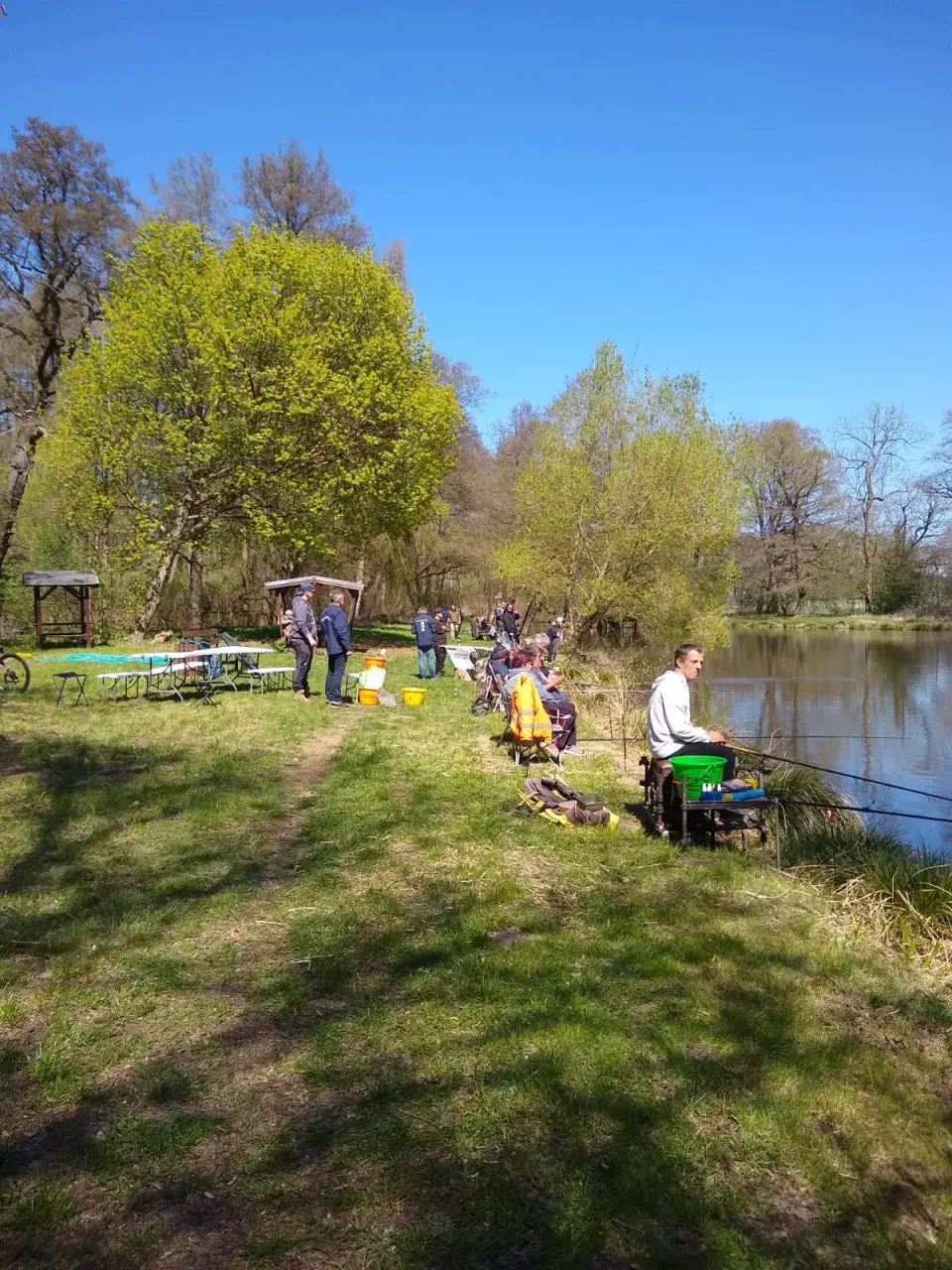 Junger Angler mit gefangener Rotfeder am Teichufer